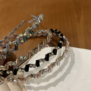 Gros plan de quatre serre-têtes ondulés fins avec perles de cristal et strass brillants
