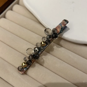 Detailed macro view of handmade beaded hair clip with vintage floral fabric and grey crystals