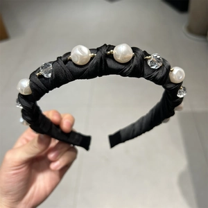 Détail d'un serre-tête en soie plissée avec perles blanches et cristaux étincelants