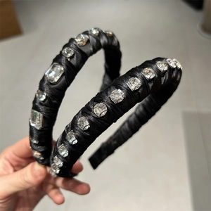 Detailed macro view of black satin headband featuring sparkling clear rhinestones set