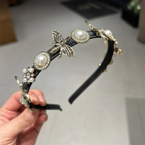 Detail of thin headband with white pearls, golden bees, and sparkling rhinestones