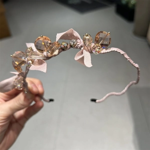 Detail of pink silk headband featuring large faceted amber crystals and delicate bows