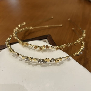 Detail eines goldenen Blumen Stirnbands mit rosa Blüten und Herz Strass Haarschmuck