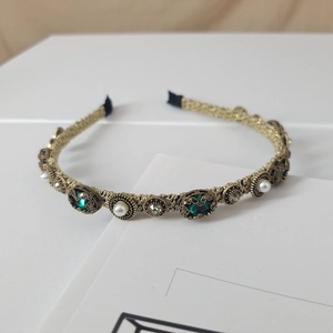 Detail of baroque pearl headband with green crystals and gold metal texture
