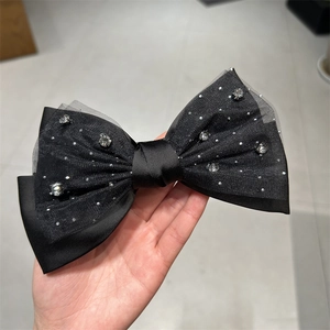 Detailaufnahme der schwarzen Satin-Haarschleife mit feinem Netz und glitzernden Strasssteinen