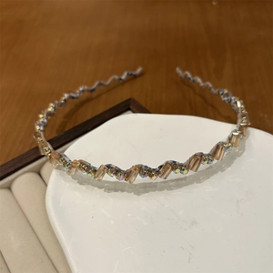 Détail macro du serre-tête ondulé avec cristaux champagne et strass irisés étincelants