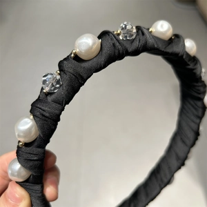 Détail d'un serre-tête en satin noir avec perles et cristaux pour un style de luxe élégant