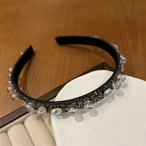 Dettaglio di strass in cristallo e perline iridescenti su un cerchietto nero di lusso