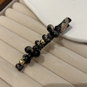 Detail of handmade beaded hair clip with dark green fabric and faceted crystals
