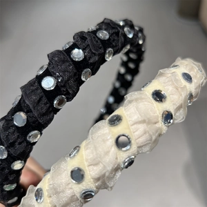 Close-up of pleated satin headbands in black and beige with sparkling rhinestones