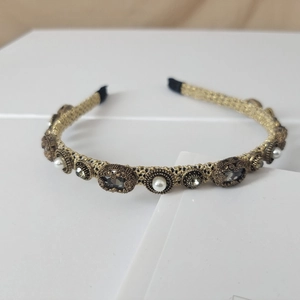 Detailed macro of vintage gold mesh headband featuring pearls and faceted rhinestones