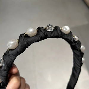 Gros plan détaillé d'un serre-tête en satin avec perles et cristaux sur tissu noir