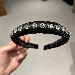 Close-up of black satin padded headband decorated with large sparkling round rhinestones