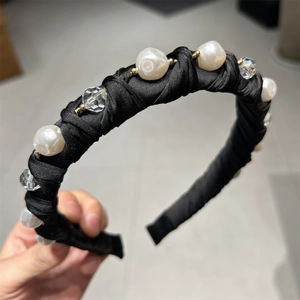 Gros plan sur un serre-tête en satin noir orné de perles blanches et de cristaux