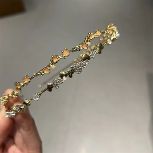 Detail von goldenen Haarreifen mit rosa Emaille-Blumen und Strassherzen mit Perlen