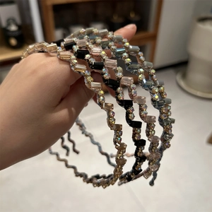 Gros plan de serre-têtes ondulés en métal avec strass brillants et perles de cristal