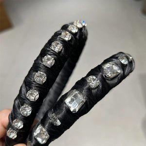Detailed close-up of wide black satin headband with large square and round sparkling crystals