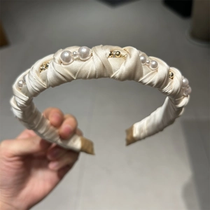 Detailed shot of cream satin headband with white pearls and gold accents