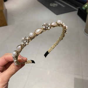 Detailed macro view of gold metal headband featuring white pearls and sparkling rhinestones