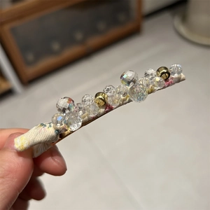Detail of handmade beaded floral hair clip featuring crystal beads and fabric texture
