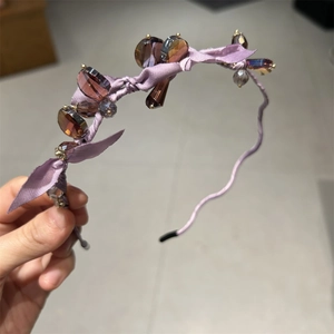 Detail of purple ribbon headband featuring faceted crystal beads and wavy metal structure