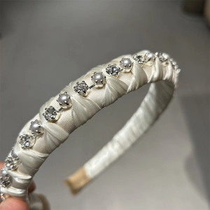 Detailed view of hand-woven cream satin headband with sparkling crystals and pearls
