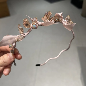 Detailed close-up of pink fabric headband with champagne crystal flower accents
