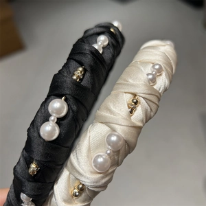 Close-up of satin twisted headband with faux pearls and golden beads for elegant hair styling