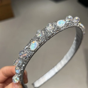 Dettaglio macro della fascia con strass, cristalli colorati e tessuto ondulato argento