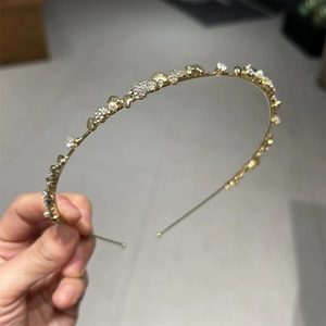 Detailaufnahme des goldenen Haarreifens mit glänzenden Strasssteinen und weißen Kunstperlen