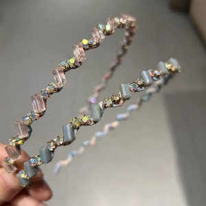 Gros plan de serre-têtes ondulés en métal avec cristaux roses et gris et strass colorés