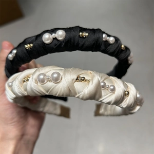 Close-up of black pleated fabric headband with faux pearls and gold beads detail