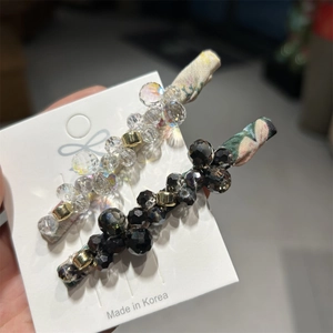 Detail of two handmade beaded hair clips with gradient acrylic beads on white card