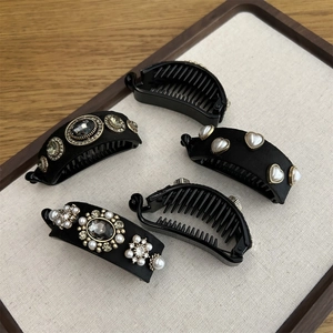 Detailed macro view of black matte banana clips with pearls and rhinestones on a display board