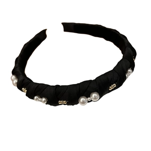 Elegant black satin headband with faux white pearls and gold beads on white background