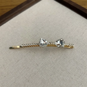Detailed view of gold hair clip with large heart crystals and sparkling rhinestones