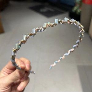 Détail du serre-tête ondulé avec cristaux bleus et strass sur une monture fine