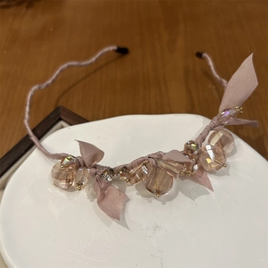 Detail of champagne crystal headband with chiffon bow on elegant ceramic tray