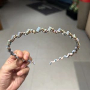 Détail d'un serre-tête floral ondulé orné de pierres bleues et de strass brillants