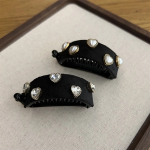 Close-up of black velvet banana hair clips with pearl hearts and rhinestone details