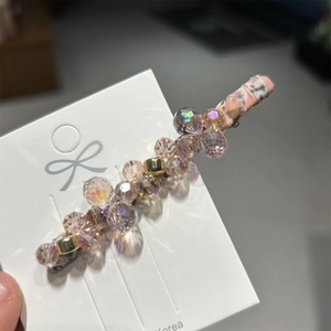 Close-up of handmade pink and purple crystal beaded hair clip with floral fabric detail