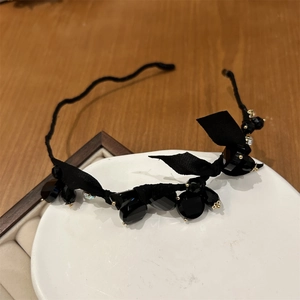 Close-up of elegant black beaded headband with faceted crystals and a satin ribbon bow
