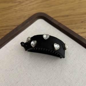 Detail of black velvet banana hair clip with five sparkling heart-shaped rhinestones