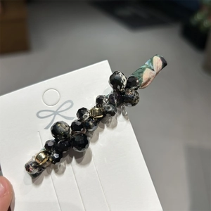 Detail of handmade beaded hair clip with black faceted crystals and floral fabric wrap