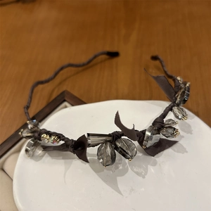 Detailed view of crystal beaded headband with dark brown ribbon and wave frame on ceramic plate