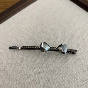 Close-up of grey crystal bow hair clip with rhinestones and black metal base