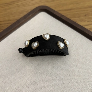 Detailed macro view of black velvet banana hair clip with heart pearls and gold metal trim