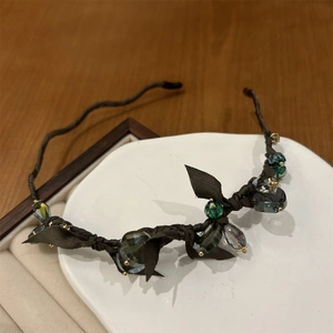 Detailed macro view of vintage crystal headband with green and brown beads on ceramic dish