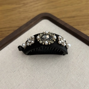 Elegant banana clip with black velvet, grey gemstone, pearls and rhinestones on a tray