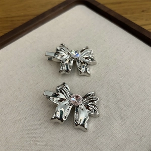 Detail of silver metallic bow hair clips with iridescent white and pink center stones